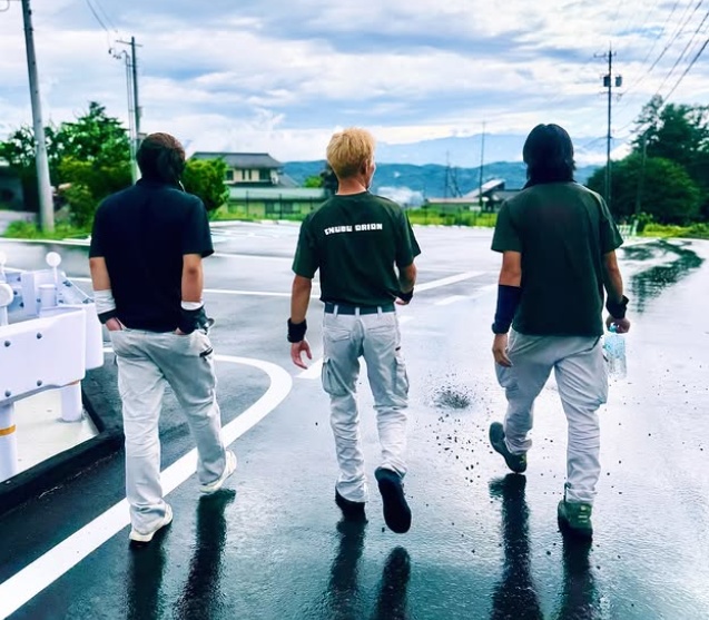 仲間と車のそばで笑顔で過ごすスタッフ